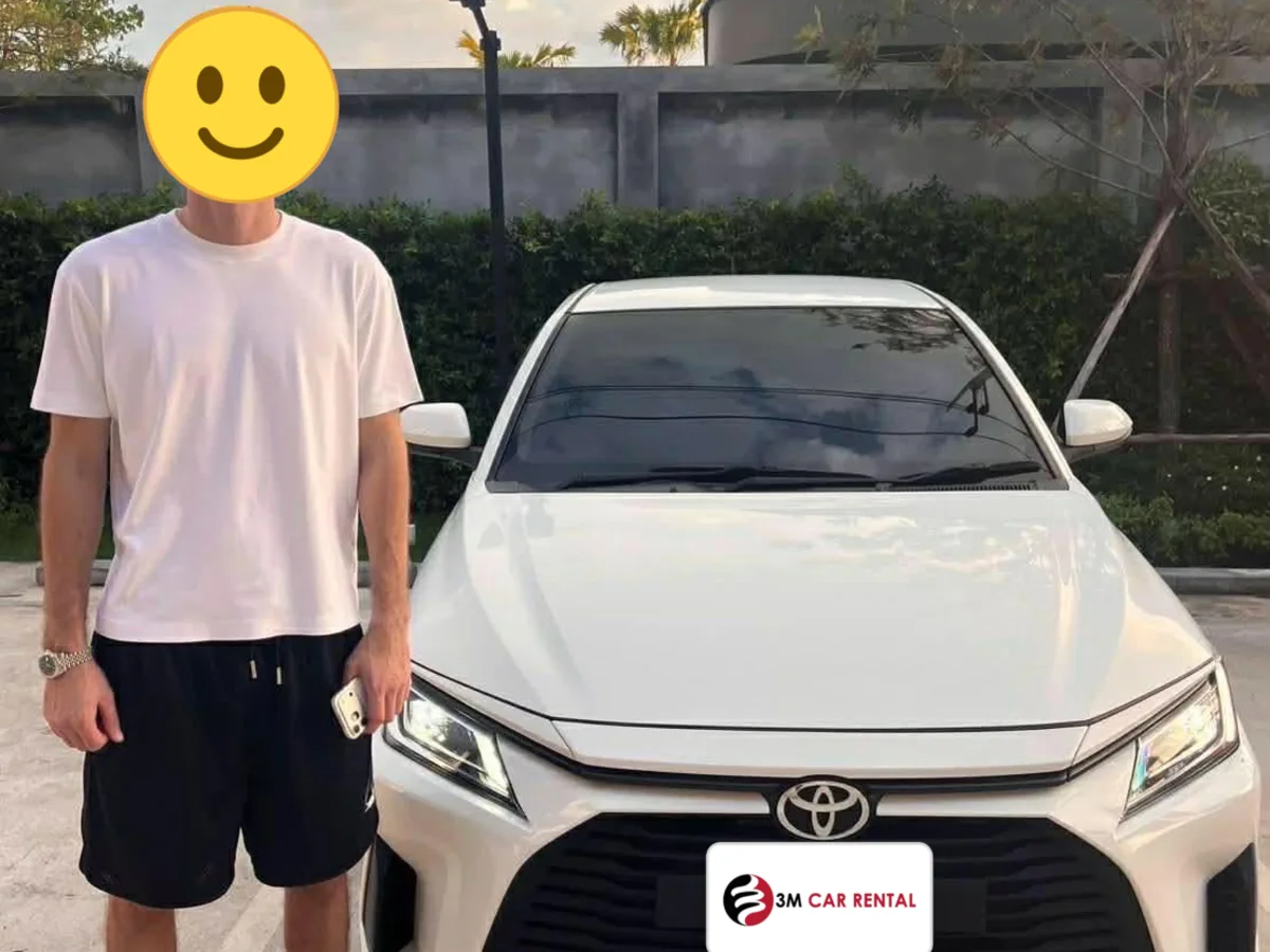 Guest with a white Toyota Yaris Ativ rental car at sunset in Phuket