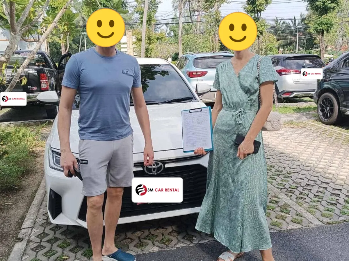 Two guests collecting their white Toyota rental car in Phuket
