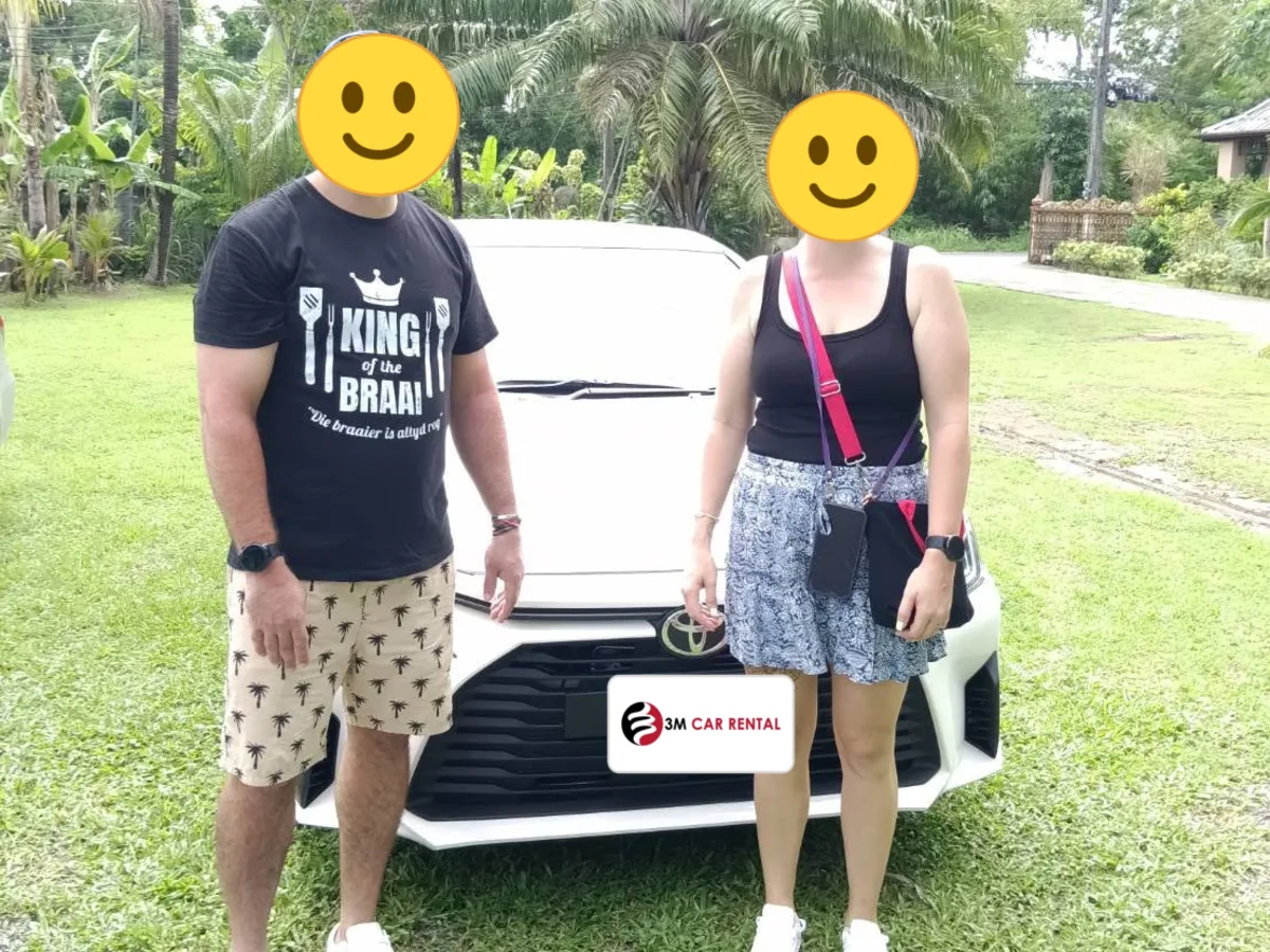 Two happy guests with their white Toyota rental car on a Phuket lawn